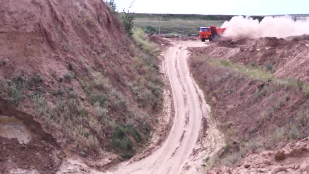 大卡车经过后, 乡村道路上的灰尘。现场。重型红色挖掘机在采石场尘土飞扬的土路上行驶, 背后留下了大量灰尘. — 图库视频影像