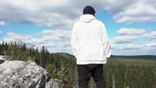 Vista trasera del hombre de pie en el acantilado de la montaña — Vídeo de stock