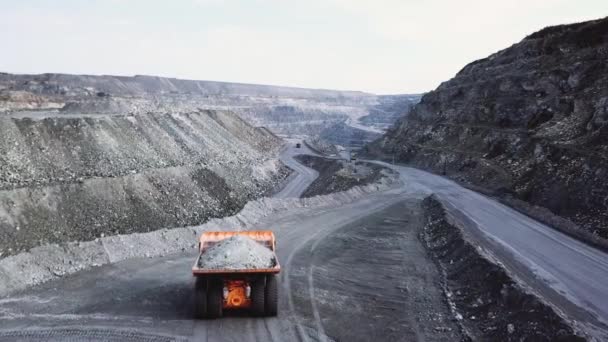 ダンプ トラックは、採石場です。道路露天掘りで瓦礫とオレンジ色のダンプ トラックを運転の平面図です。採鉱産業の重い輸送 — ストック動画