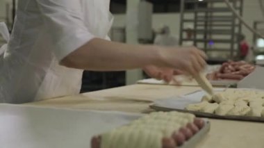 Ekmek ve hamur inişli çıkışlı bir fırıncı kadın ham puf böreği sarılı sosis için kapatın. Çiğ sosis hamur içinde kadın baker eller, gıda hazırlama kavramı tarafından haddelenmiş.