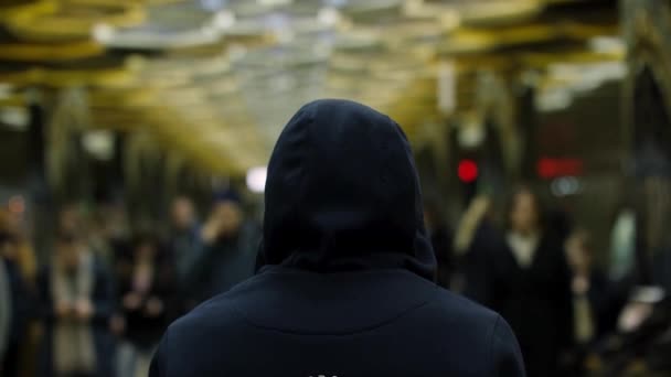 Bakifrån av en man med en mörk blå hoodie på stående framför en publik på stationen, motstånd koncept. Närbild för mannen tillbaka framför många människor i tunnelbanan. — Stockvideo