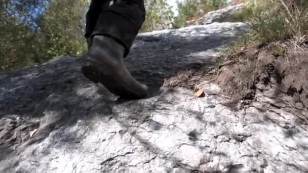 Detail člověka holínky při pěší turistiku na stezce v horách v uschlé trávy. Tramp muž nohy lezení strmých svahu skály. — Stock video