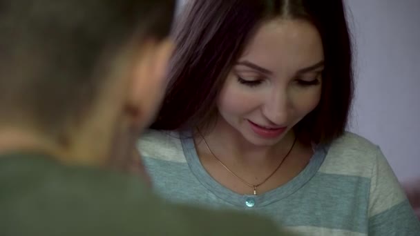Close up of smiling, excited young woman looking at male partner, positive emotions concept. Beautiful, nervous brunette looking into the eyes of a man and smiling on grey background. — Stock Video