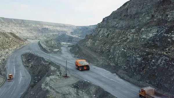 La camioneta está en la cantera. Vista superior de la conducción de camión volquete naranja con escombros en la carretera a cielo abierto. Transporte pesado en la industria minera — Foto de Stock