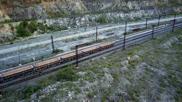 ディーゼル機関車は石灰岩採掘のため採石場の背景に割栗石でいっぱい貨車を推進しています。 — ストック写真