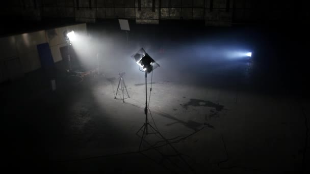 Dark photo studio with light spotlights. Spacious dark room with supplied floodlights and camera on tripod ready for professional shooting — Stock Video