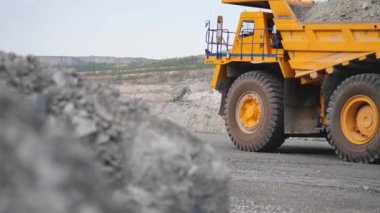 Kamyon sürüş kariyer yolu üzerinde. Damperli kamyon açık çukura mayınlı cevheri taşır. Arka plan açık beyaz çok aşamalı ocağı üzerinde araştırma sektöründe ağır büyük nakliye