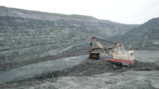 挖掘机在露天矿中用泥土填充自卸车。露天矿矿山的重型机械工程 — 图库视频影像