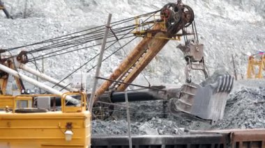 Tarak ve cevher ile tren. Ekskavatör cevheri ile demiryolu araçları açık çukurun arka planda doldurur. Madencilik sektöründe ağır nakliye