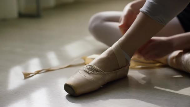 Ballerinas láb részlete. Balerina előkészítése képzés, és az árukapcsolás szalag a pointe cipők ül a emelet-ban okos napfény