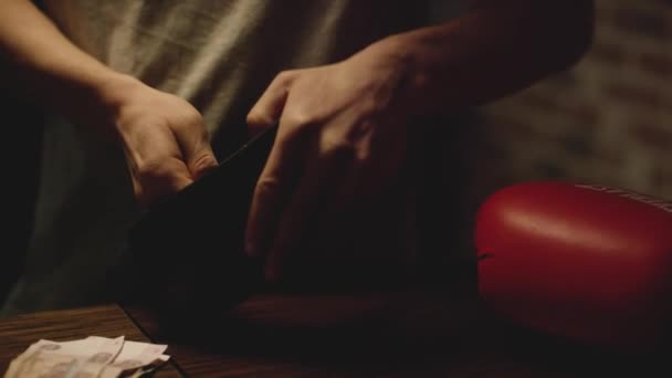 L'homme considère son argent. Jeune étudiant sort de son portefeuille tout son argent et compte en espèces avec des pièces sur la table — Video