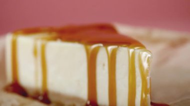 Cheesecake tatlı şurubu ile Close-up. Çerçeve. Pembe şekerlemeler şurubu ile ıslatılmış lezzetli tatlı cheesecake