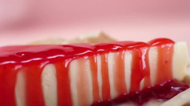 Cheesecake tatlı şurubu ile Close-up. Çerçeve. Pembe şekerlemeler şurubu ile ıslatılmış lezzetli tatlı cheesecake