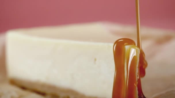 El primer plano del pastel de queso se vierte salsa dulce. Una trampa. Pastel de queso apetitoso ingeniosamente regado con caramelo dulce. Concepto de postres — Vídeo de stock
