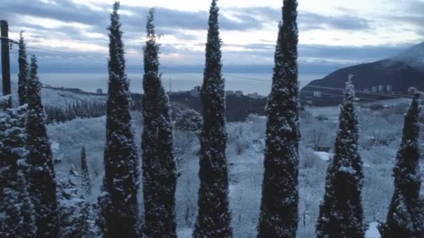 Vista superior de la ciudad cerca del mar en invierno. Le dispararon. Ampliaciones nevadas en la zona montañosa cerca de la ciudad — Vídeos de Stock