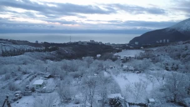 Bovenaanzicht van de stad in de buurt van de zee in de winter. Schot. Besneeuwde uitgestrekte in het bergachtige gebied in de buurt van de stad — Stockvideo