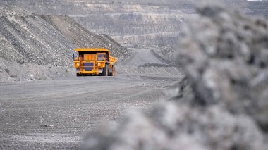 Kamyon sürüş kariyer yolu üzerinde. Damperli kamyon açık çukura mayınlı cevheri taşır. Arka plan açık beyaz çok aşamalı ocağı üzerinde araştırma sektöründe ağır büyük nakliye