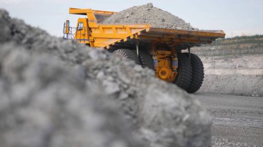 Kamyon sürüş kariyer yolu üzerinde. Damperli kamyon açık çukura mayınlı cevheri taşır. Arka plan açık beyaz çok aşamalı ocağı üzerinde araştırma sektöründe ağır büyük nakliye