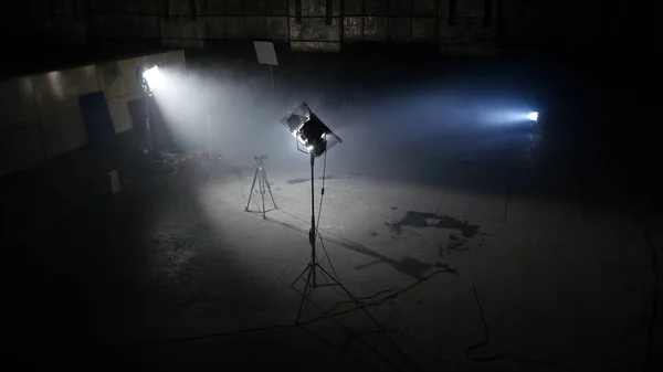 Σκοτεινή φωτογραφία studio με φως σποτ. Ευρύχωρο σκοτεινό δωμάτιο με παρεχόμενο προβολείς και φωτογραφική μηχανή στο τρίποδο έτοιμη για επαγγελματική σκοποβολή — Φωτογραφία Αρχείου
