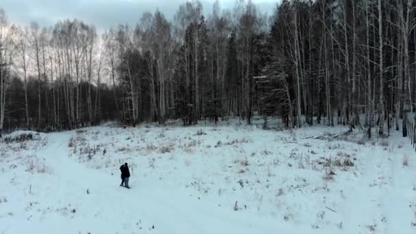 Um par de pessoas perto de uma floresta nevada. Estoque. Casal de pessoas em frente à floresta no inverno — Vídeo de Stock