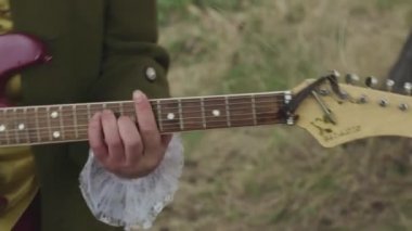 Adam için eski moda kostüm Rokoko şekilde solmuş çim zemin üzerine mor bir elektrik gitar ile kapatın. Hisse senedi. Eski giysiler içinde sanatçı varek asma gitar çalıyor.