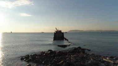 Paslı harap gemi mavi, bulutlu gökyüzü ve parlayan güneş arka plan mavi bir deniz battı. Vurdu. Suya yansıyan güneş ışığı ile deniz sahil yakınında düşen tekne.