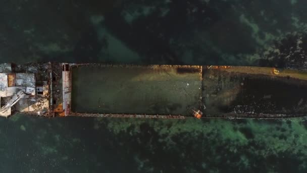 Aerial top view for wrecked ship along the rocky coast in blue water. Shot. Old sunk boat near sea shore, view from above. — Stock Video