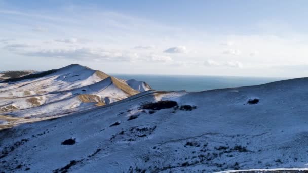 Vista aérea de montañas nevadas, mar, cielo nublado. Le dispararon. Colinas cubiertas de nieve junto al mar — Vídeos de Stock