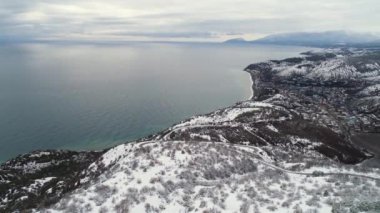 Güzel kış deniz karlı alanları, orman ve gri, bulutlu gökyüzü arka plan üzerinde mavi deniz. Vurdu. Kış sahil şeridine karlı ağaçlar ve alanlar için hava.