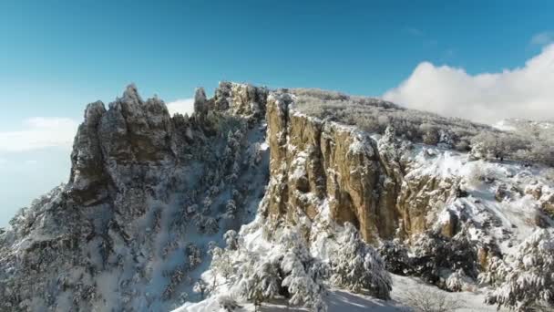 Favoloso paesaggio invernale, montagne e foresta ricoperta di neve su sfondo cielo blu brillante. Gli hanno sparato. ripida scogliera con persone che risalgono il sentiero innevato invernale tra gli alberi innevati . — Video Stock