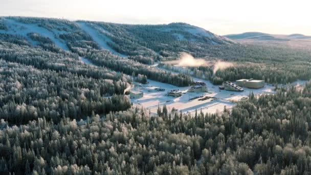 Een prachtige luchtfoto van mensen een besneeuwde berg op Skigebied Skiën op de blauwe hemelachtergrond. Beeldmateriaal. Zonnige winterdag in groen dennenbos bomen en besneeuwde Alpen rotshellingen met kabelbaan. — Stockvideo