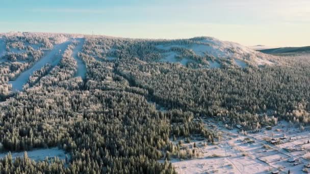 Eine schöne Antenne von Menschen, die in einem schneebedeckten Berg im Skigebiet auf blauem Himmelshintergrund Ski fahren. Filmmaterial. sonnig, Wintertag im grünen Pinienwald und schneebedeckten Alpenhängen mit Standseilbahn. — Stockvideo