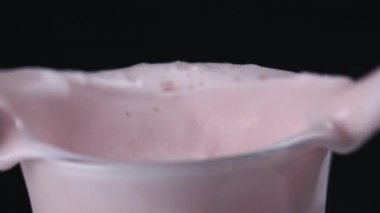 Cam düşen çilek ile lezzetli milkshake close-up. Çerçeve. Siyah izole