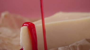 Close-Up lezzetli dilim peynirli kek çilek reçeli ince dere tarafından dökülür. Çerçeve. Pink izole