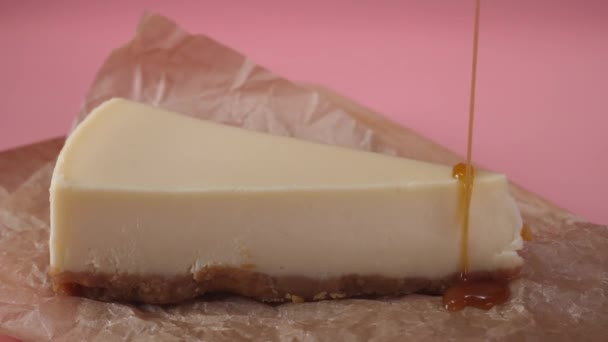 Deliciosa fatia de cheesecake, que é derramado por fina corrente de molho de caramelo. Moldura. Close-up — Vídeo de Stock