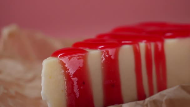 Close-up van eigengemaakte cheesecake bekroond door aardbeienjam. Geïsoleerd op roze — Stockvideo