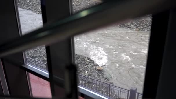 Detailní záběr pro kovové zábradlí s stream mimo okno, pohled od schodů. Úzký záliv, kamenité silnici za oknem. — Stock video