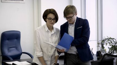 Proje yönetimi. Resmi kıyafetlerle neşeli genç iş ortakları birlikte çalışıyoruz. Sevimli kadınla kağıtları kalem tutma ve klasör gülümseme ile seyir Afrika adam tutuyor