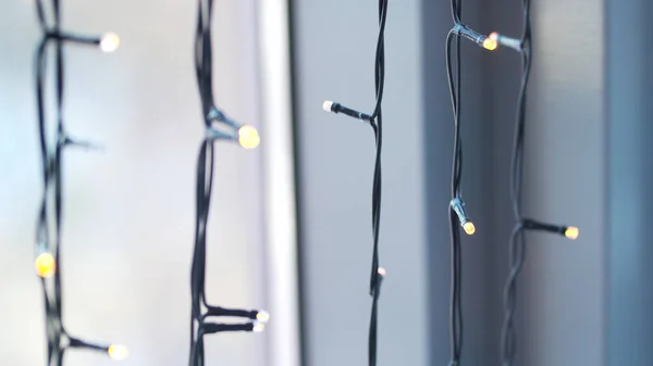 Beautiful garland with lights close up. selective focus of Christmas warm gold garland lights. Christmas lights on window background — Stock Photo, Image