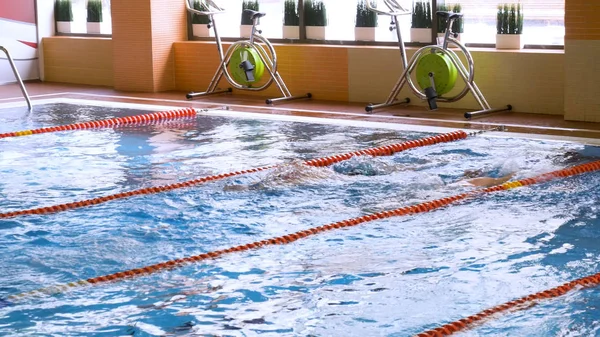 Muchos nadadores entrenan estilo libre en una piscina, estilo de vida saludable, concepto deportivo. Gente nadando en aguas azules y cristalinas de la piscina . —  Fotos de Stock