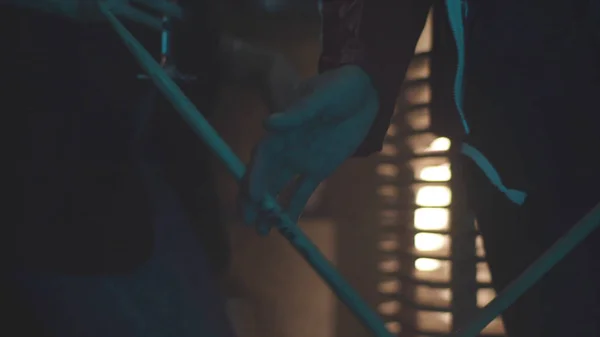 Close up van de man met trommel stok tussen vingers en het spinnen, rock muziek concept. Jonge drummer met een roterende trommel stok in zijn hand op rood vuur lichte achtergrond wazig. — Stockfoto