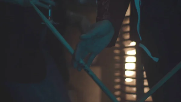 Close up of the man holding drum stick between fingers and spinning it, rock music concept. Young drummer with a rotating drum stick in his hand on blur red fire light background. — Stock Photo, Image