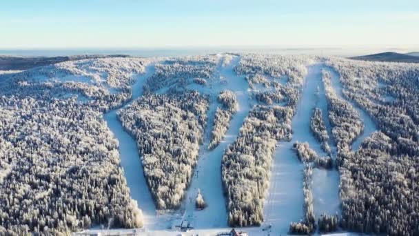 Widok z góry z panoramą narciarskich stokach. Materiał filmowy. Ośrodek narciarski u podnóża góry ze stoków i wyciągów narciarskich na tle horyzont i niebieskie niebo. Aktywny wypoczynek zimą — Wideo stockowe