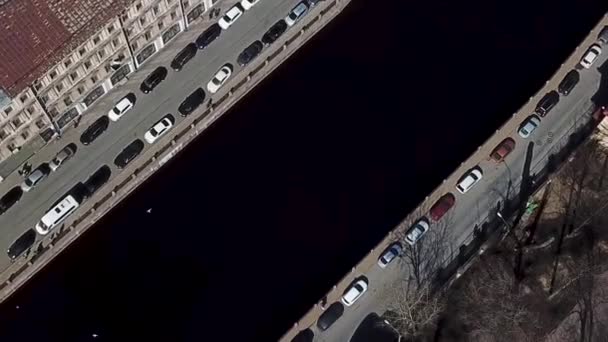 Top view of the road with parked cars and people walking along the river channel. Aerial for water canal with parked vehicles in the city in a sunny, summer day. — Stock Video
