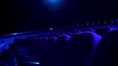 Rahat koltuklar mavi ışık ile karanlık, boş sinema salonu. Sinema koltuğu satırlar için yakın çekim.