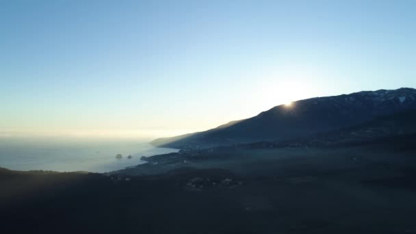 Sol de la mañana que sube sobre una montaña cerca del mar en el fondo azul del cielo, belleza de la naturaleza. Le dispararon. Pintoresco amanecer en la costa del mar, valle y roca alta . — Vídeos de Stock