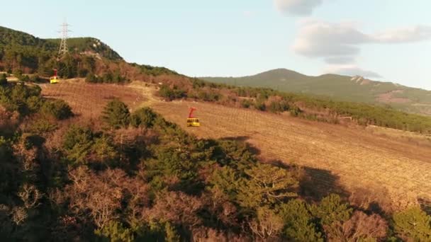 Malebný pohled lanovka s kabinou nad podzimní les proti modré oblohy jasno. Střela. Horská krajina. — Stock video