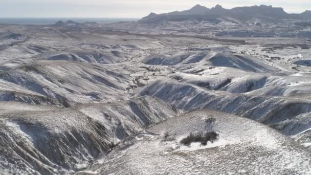 Vista aérea sobre laderas montañosas cubiertas de nieve cerca del mar contra el cielo nublado. Le dispararon. Paisaje invierno . — Vídeos de Stock