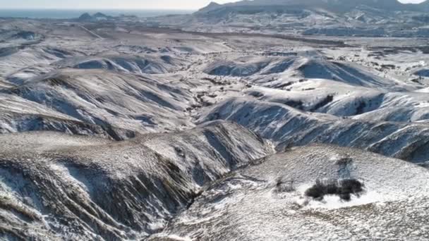 Luchtfoto op berghellingen vallende sneeuw in de buurt van de zee tegen de bewolkte hemel. Schot. Winterlandschap. — Stockvideo