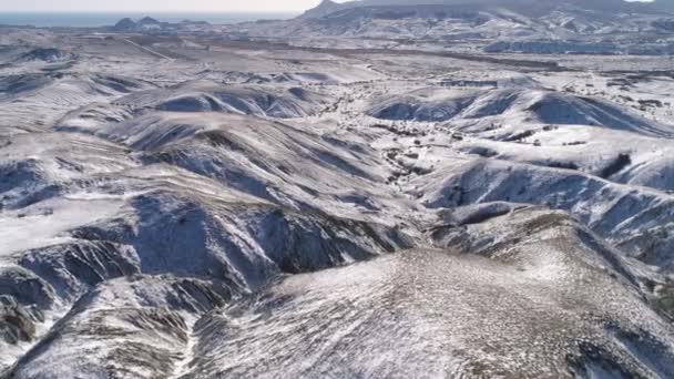 Hermosa vista sobre las laderas nevadas de las montañas cubiertas de árboles y arbustos cerca del mar contra el cielo nublado. Le dispararon. Paisaje invierno . — Vídeos de Stock